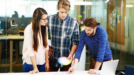 diseñadores gráficos que interactúan entre sí mientras trabajan en la oficina