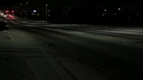 cars driving down a main road in a suburban area during a snowstorm