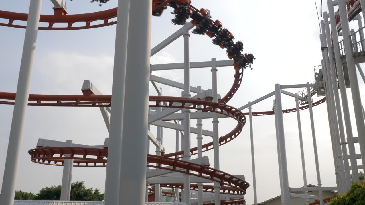 Ripresa al rallentatore del treno delle montagne russe che scende a spirale mentre segue il circuito delle montagne russe, Dream World, Thailandia