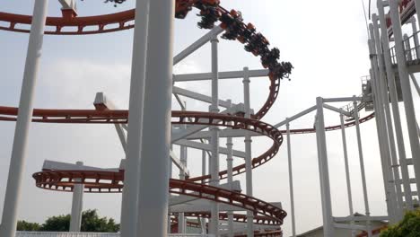 slow motion shot of roller coaster train going down in a spiral while following the roller coaster circuit, dream world, thailand