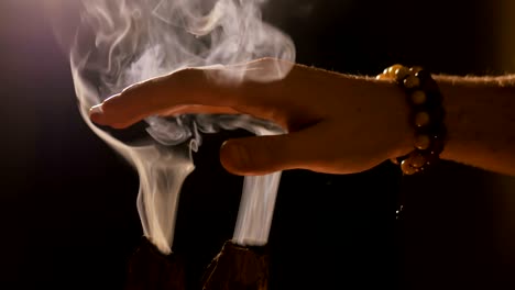 smoke from incense rises through fingers