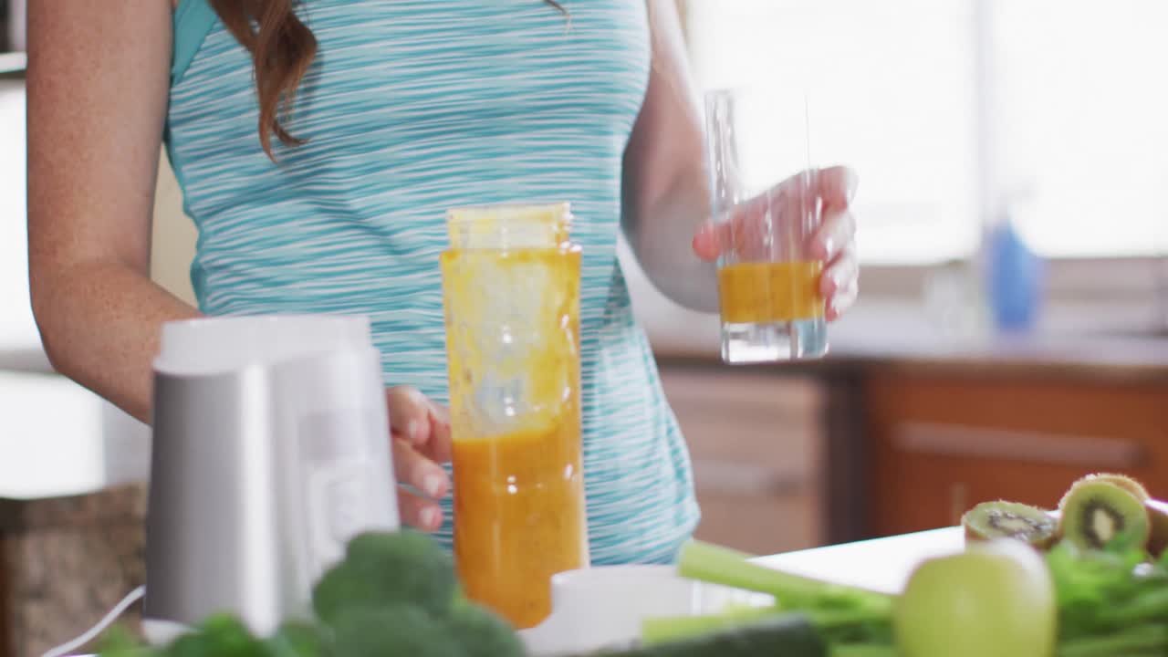 Caucasian woman drinking healthy drink in kitchen