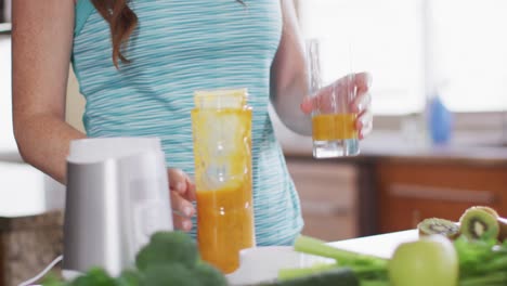 mujer caucásica bebiendo una bebida saludable en la cocina
