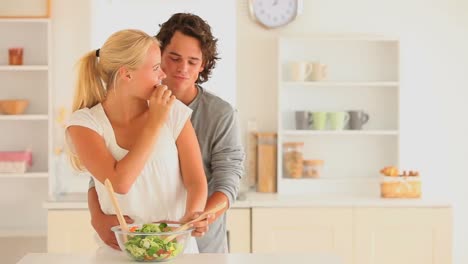 una pareja feliz preparando su ensalada