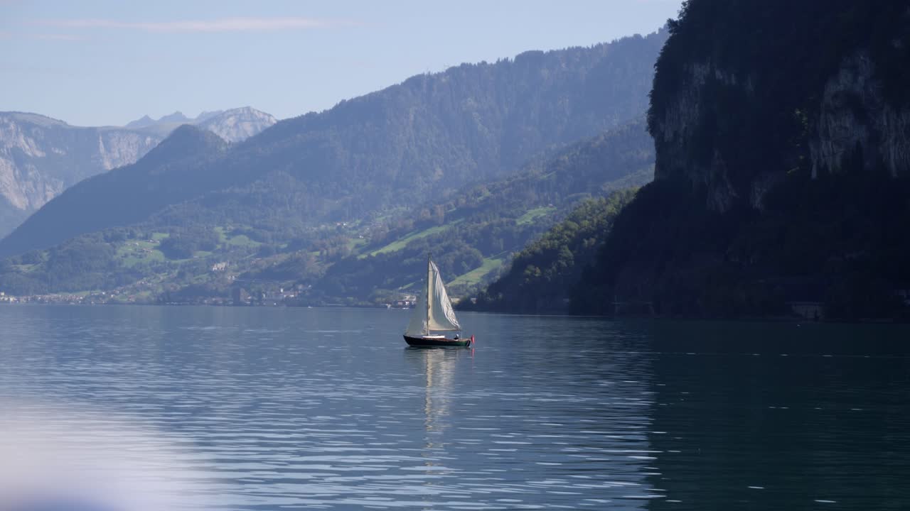 toma amplia cinematográfica de un velero en el lago walensee, telón de fondo alpino, cámara lenta