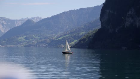 cinematic wide shot of sailboat on lake walensee, alpine backdrop, slowmo