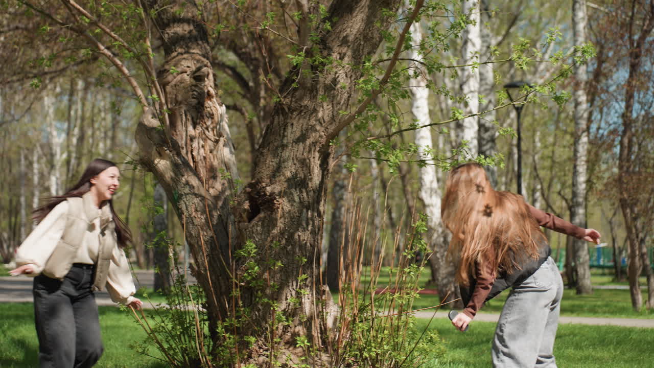 친구들이 경주하는 밝은 공원, 즐거운 달리기와 친근한 경쟁으로 가득한 햇살 가득한 공원, 다양한 배경을 가진 친구들과 함께 나무 주위를 행복하게 뛰어다니는 빨간 머리 아이들