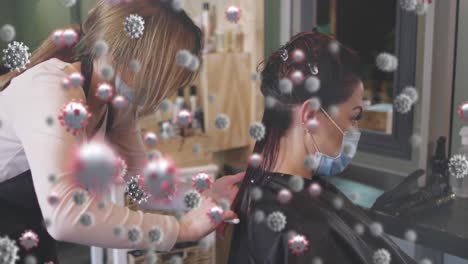 animación de células de coronavirus sobre una peluquera caucásica y una mujer que usa máscaras faciales