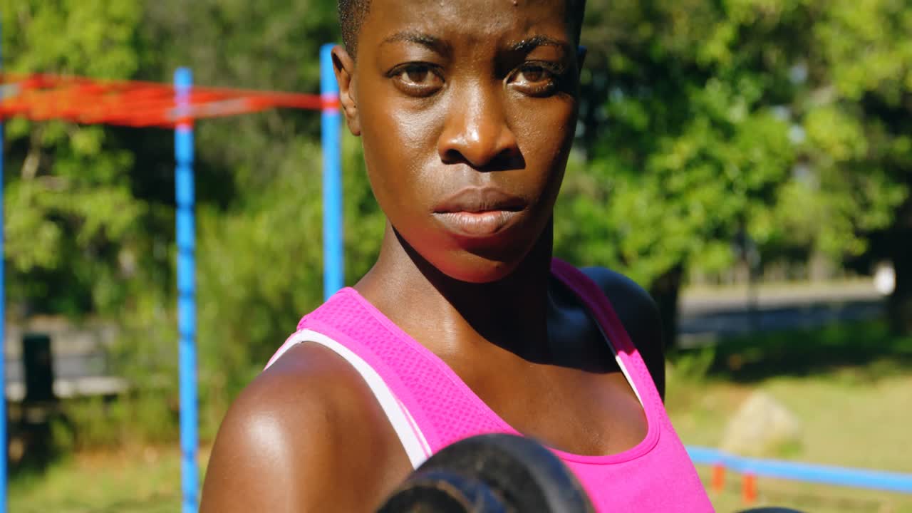Female athlete exercising with dumbbell in the park 4k