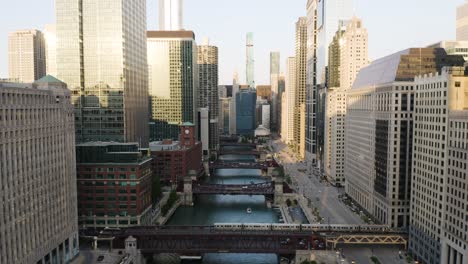 drone flies backwards as train crosses bridge over river in downtown chicago loop