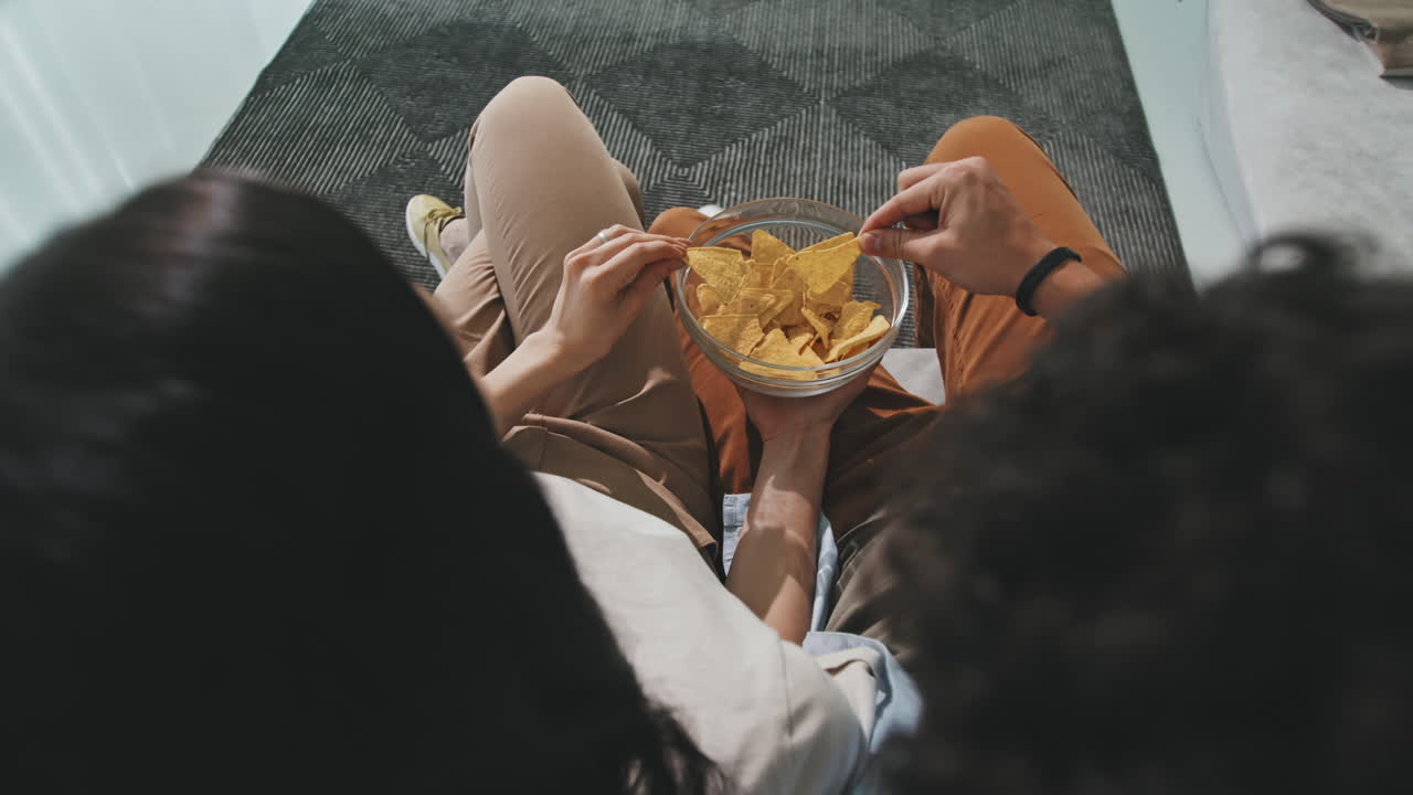 Top-View Of Couple Eating Nachos While Watching TV