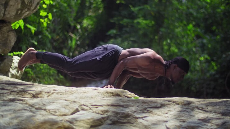 Young strong black man exercising and bodybuilding outside in nature