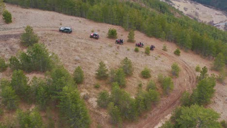 aerial tracking shot following a group of off-road vehicles drive up a rugged mountain trail