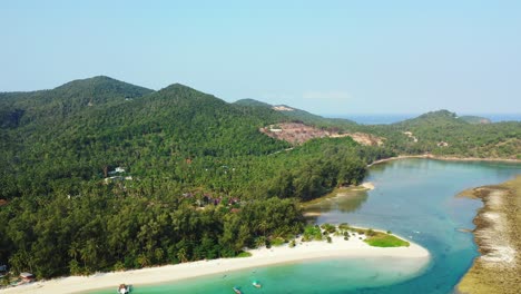 Beautiful-bay-with-calm-clear-water-of-turquoise-lagoon-washing-white-sandy-beach-of-tropical-island-with-trees-forest-in-Thailand