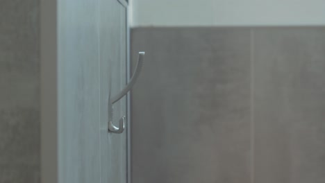 Close-up-of-hands-hanging-a-bathrobe-on-a-towel-rack-in-a-spa