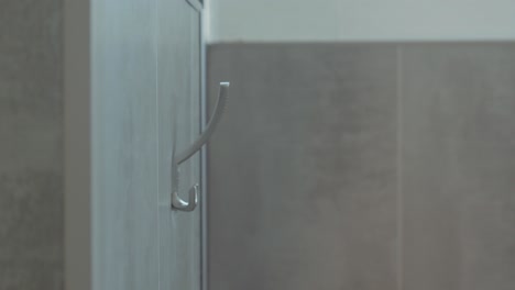 primer plano de manos colgando una bata de baño en un estante de toallas en un spa