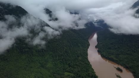 wide open aerial scenic view of a jungle river surrounded by stunning foggy mountains