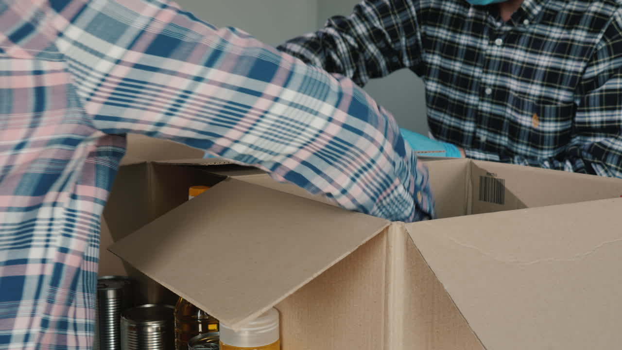 자원봉사자들은 장갑과 의료용 마스크를 착용하고 골판지 상자에 음식을 포장합니다.