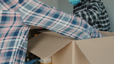 los voluntarios empacan alimentos en cajas de cartón mientras usan guantes y máscaras médicas