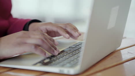 Afro-American-attractive-young-girl-with-plump-rose-lips-and-braids-in-aviator-eyeglasses-wearing-rose-coat-working-on-laptop-outside