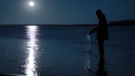 silhouette of a person at the beach at night under the moonlight