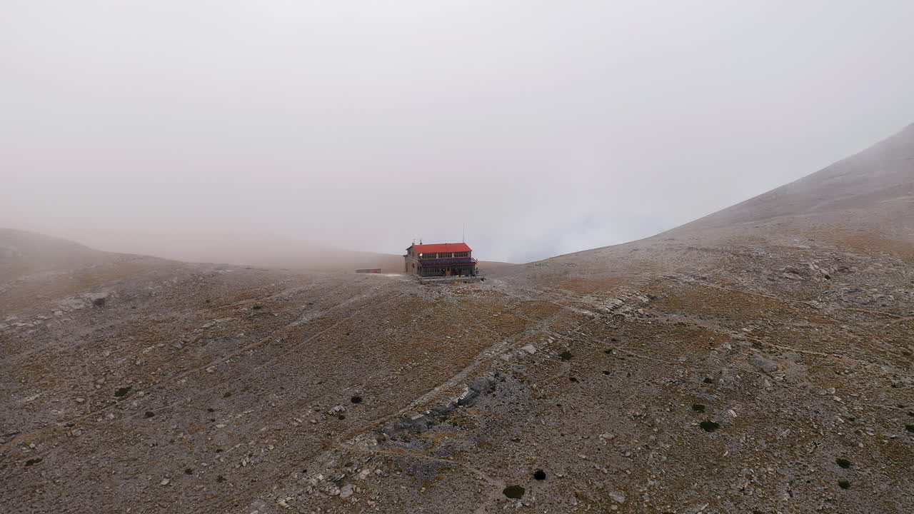 Panoramisk luftfoto av Mount Olympus om vinteren, med Giosos Apostolidis-hytten omgitt av tåke.
