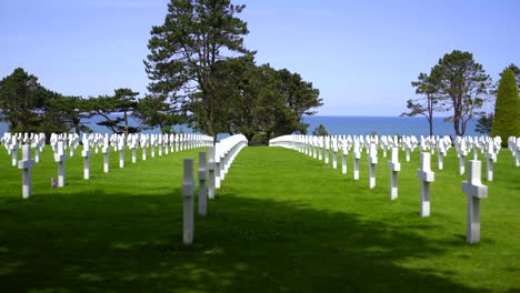 A-tracking-shot-of-rows-of-white-crosses-marking-the-graves-of-fallen-American-allied-soldiers-who-died-during-the-Normandy-invasion-at-Omaha-Beach-on-D-Day,-1944