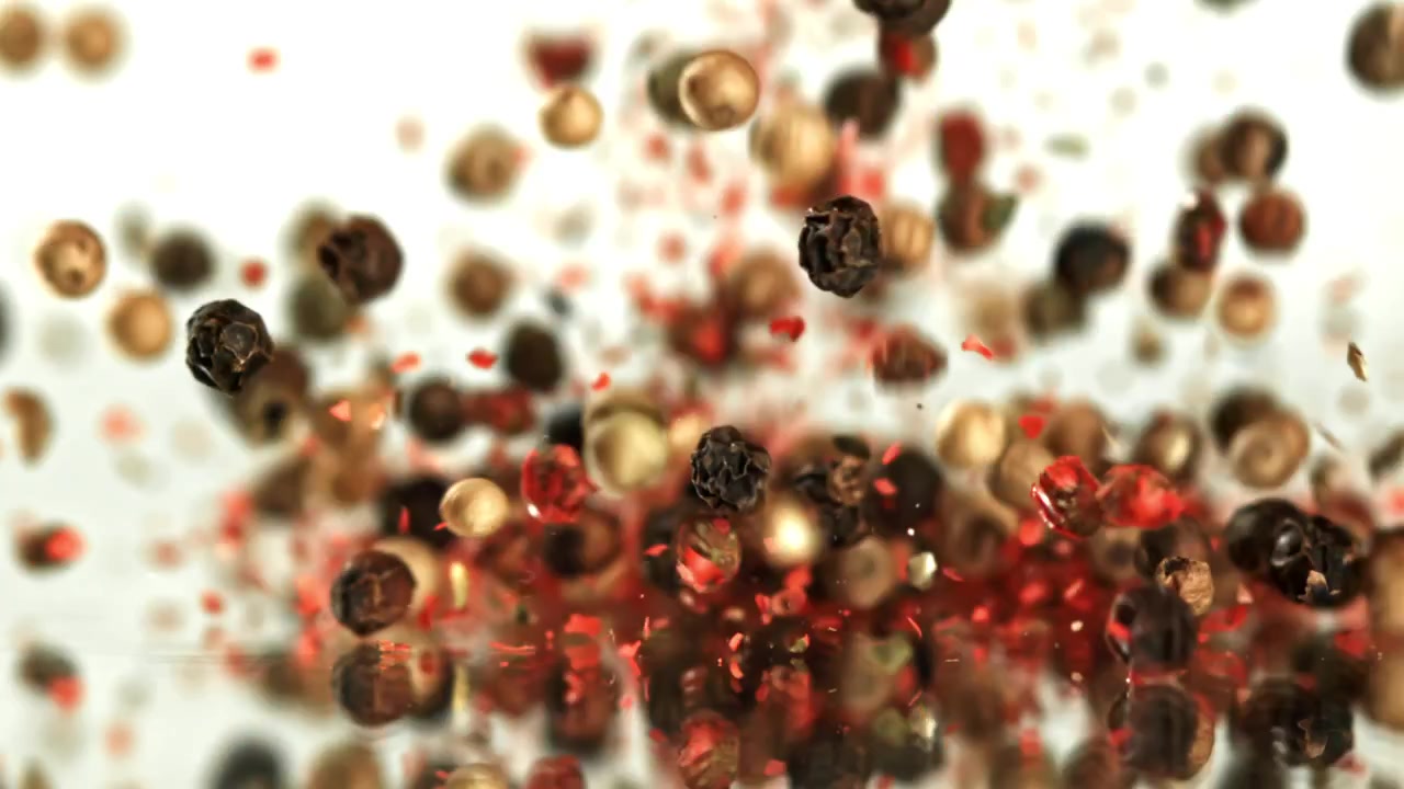 Assorted Peppercorns Falling and Mixing on White Background in Slow Motion