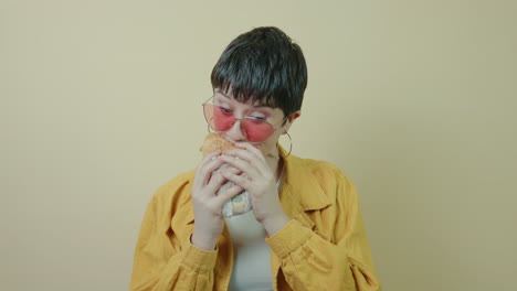 modern short-haired woman voraciously chomping a burger in a studio background