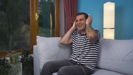 hombre mirando por la ventana y escuchando música con auriculares.