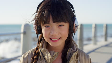 niña, cara y auriculares en el paseo por la playa