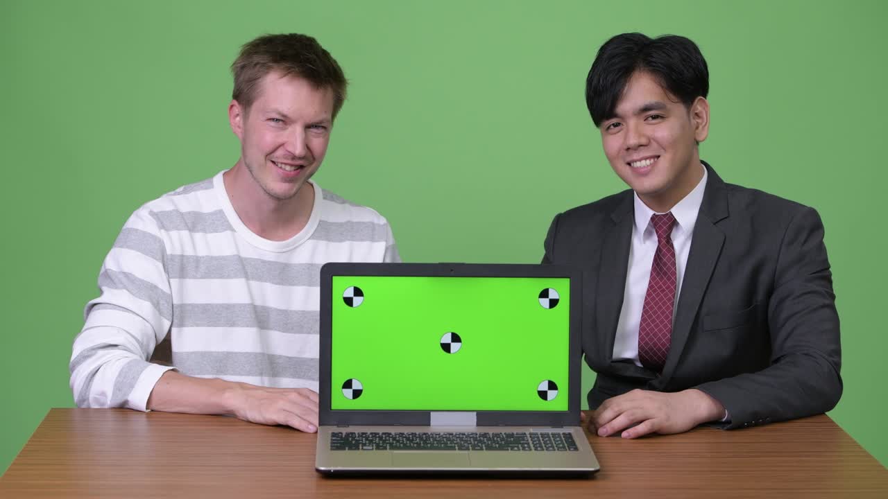 젊은 아시아 사업가와 젊은 스칸디나비아 사업가가 노트북으로 함께 일하고 있습니다.