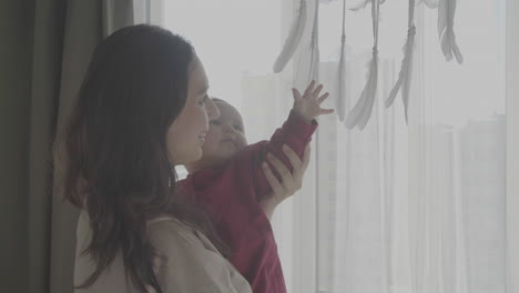 귀여운 아기를 안고 창밖을 내다보는 엄마