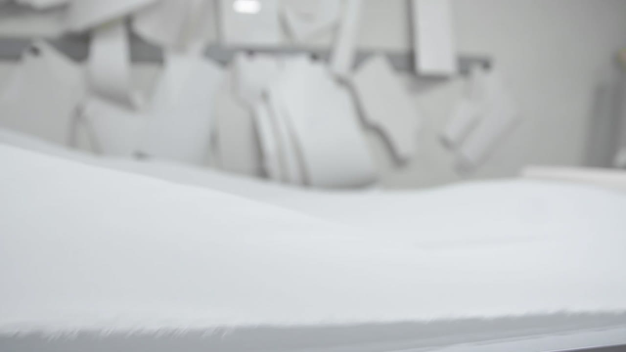 дизайнер одежды работает с измерениями на студийном столе. снято в 4k uhd . крупный план развернуть шнур из белой ткани в белом и светло-цветном шитье в замедленном движении.