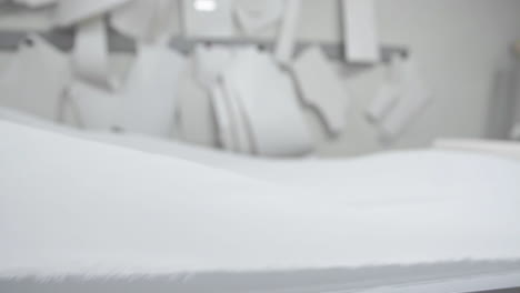el diseñador de ropa está trabajando con mediciones en una mesa de estudio. filmado en 4k uhd. en primer plano despliegan una trama de tela blanca en blanco y de color claro cosiendo en cámara lenta.