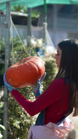 woman holding a large pumpkin in a greenhouse