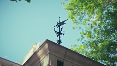 weather vane atop zagreb's meteorological post, framed by lush green trees