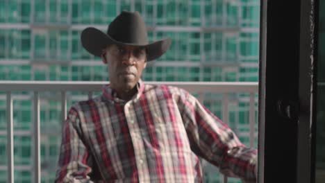 portrait shot of black man with black cowboy hat sitting