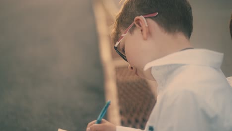 young guy draws in paper notebook with blue pen close view