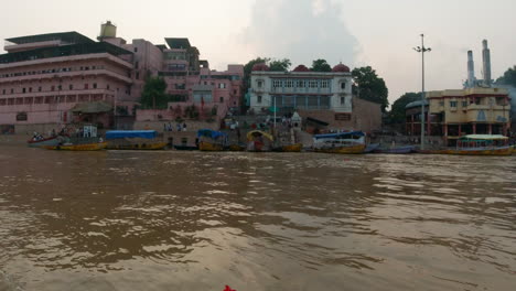 cinematic varanasi india ganges river canal boat cruise northern state people gathering on steps cremation ancient holy city ghat pradesh province landscape gray cloudy fire smoke right motion