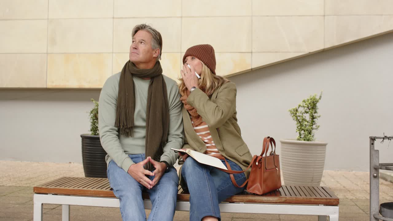 Una pareja de ancianos sentada en un banco de la plaza escribe en una libreta, señala al cielo y comparte sus descubrimientos.