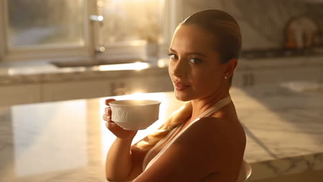 woman enjoys a warm drink in a sunlit kitchen