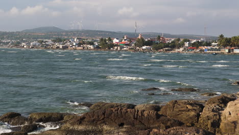 rocky coast of mui ne with a wind farm in the background, traditional vietnamese town