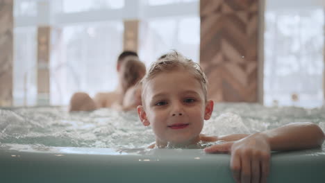 family is resting in water park and wellness center little boy is looking to camera and smiling