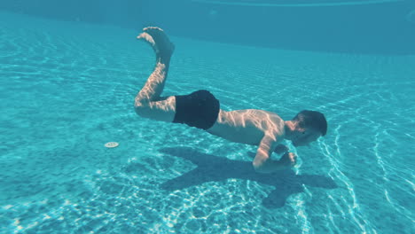 un joven nada bajo el agua en una piscina.