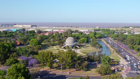 aerial dolly in view of galileo galilei planetarium building situated in a park with a pond in buenos aires, argentina