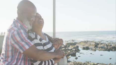 Happy-senior-african-american-couple-embracing-on-promenade-by-the-sea,-slow-motion