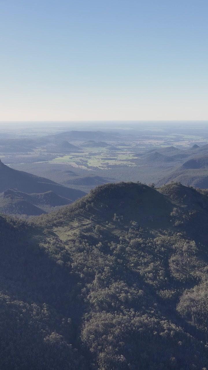 Bredt landskabsbillede af vulkanske tinder og skovklædte dale i Warrumbungle Nationalpark, Australien.