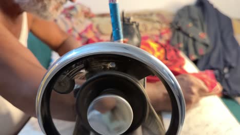 indian tailor using old stitching machine for making cloths