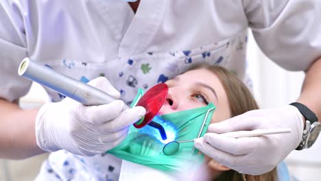 doctor treats patient teeth in modern dental clinic. photopolymer lamp in male doctor's hands.